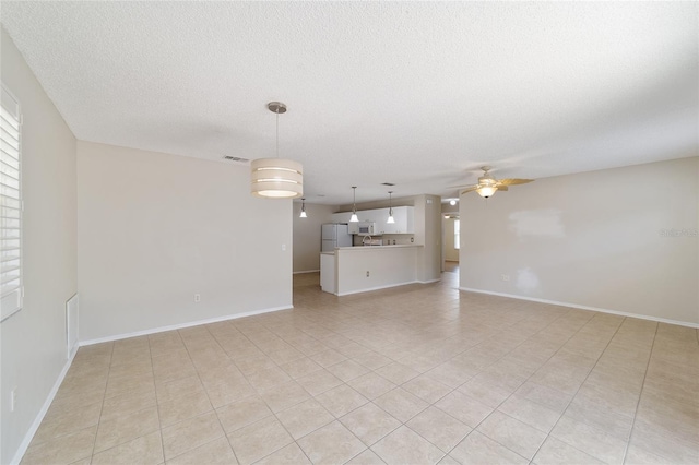 unfurnished living room featuring ceiling fan, light tile patterned floors, and a textured ceiling