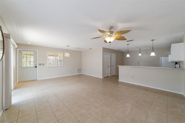 unfurnished room featuring a textured ceiling, ceiling fan, light tile patterned floors, and sink