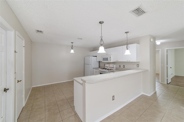 kitchen featuring kitchen peninsula, pendant lighting, white appliances, and white cabinetry