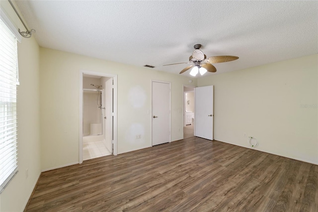 unfurnished bedroom with ceiling fan, dark hardwood / wood-style floors, a textured ceiling, and ensuite bath