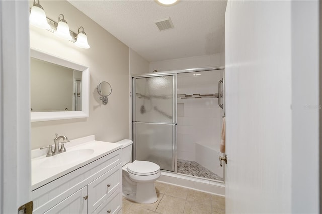 bathroom with tile patterned floors, vanity, a textured ceiling, toilet, and a shower with shower door