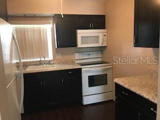 kitchen featuring sink, light stone counters, and white appliances