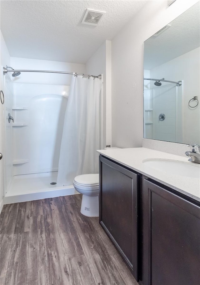 bathroom featuring curtained shower, a textured ceiling, vanity, toilet, and hardwood / wood-style flooring