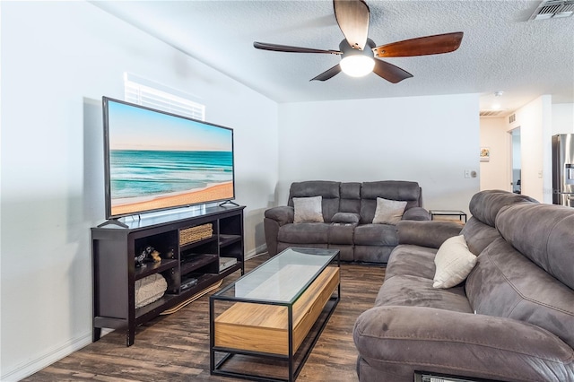 living room with a textured ceiling, ceiling fan, and dark hardwood / wood-style floors