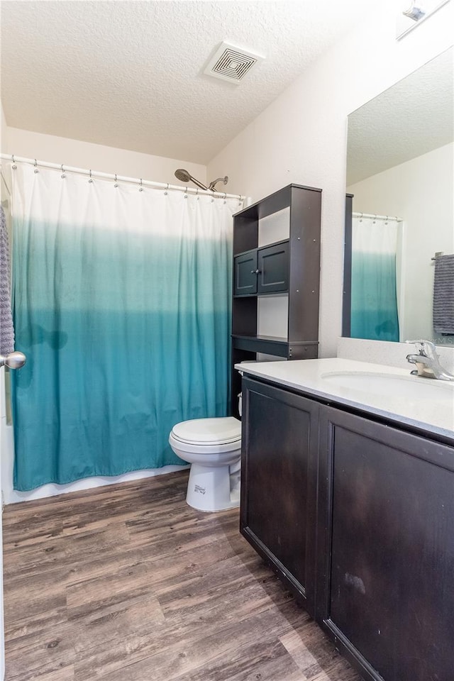 full bathroom with toilet, hardwood / wood-style floors, shower / bath combo, a textured ceiling, and vanity