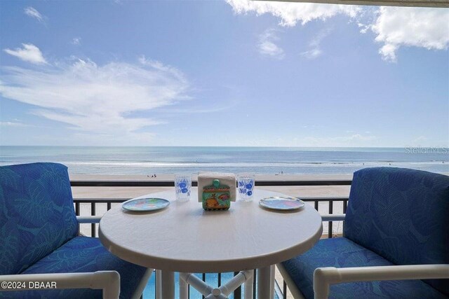 balcony with a water view and a view of the beach