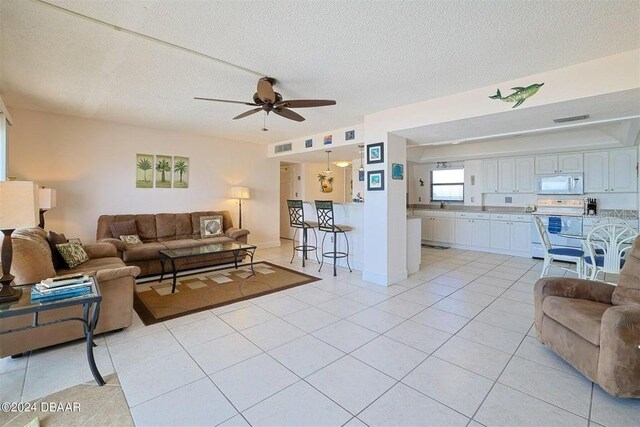 living room featuring light tile patterned floors, a textured ceiling, and ceiling fan