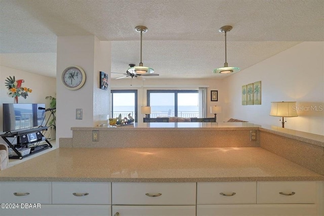 kitchen with ceiling fan, hanging light fixtures, white cabinets, a textured ceiling, and kitchen peninsula