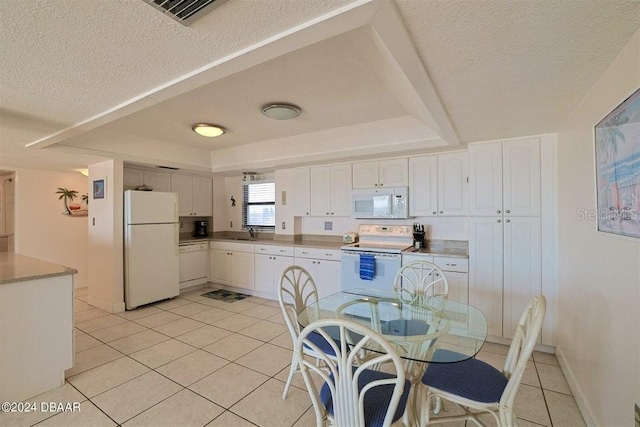 kitchen with sink, white appliances, light tile patterned floors, and white cabinets