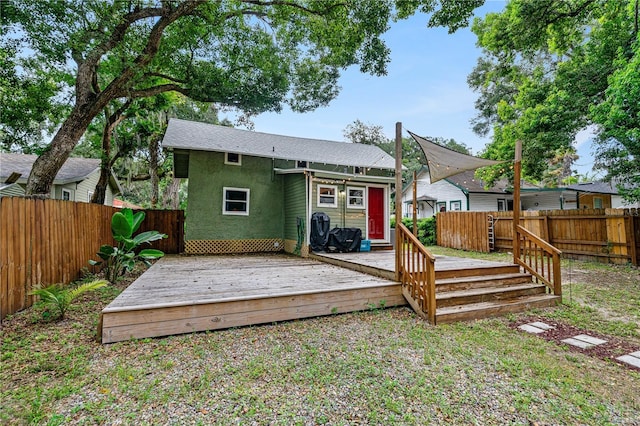 rear view of property featuring a fenced backyard, a wooden deck, and stucco siding