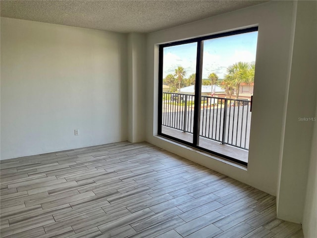 empty room featuring light wood-type flooring and a textured ceiling