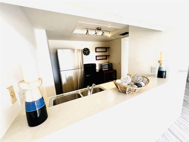 kitchen featuring stainless steel refrigerator, a tray ceiling, sink, and hardwood / wood-style floors