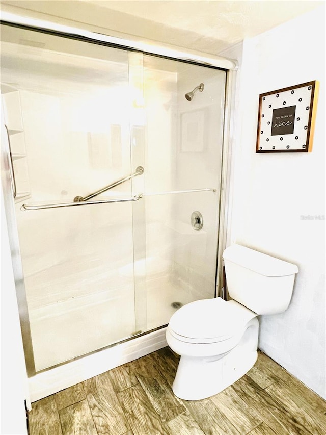 bathroom with toilet, hardwood / wood-style floors, and walk in shower