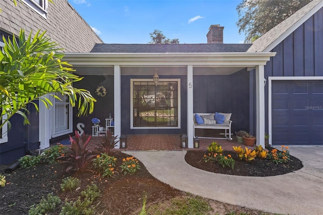 view of exterior entry featuring covered porch and a garage