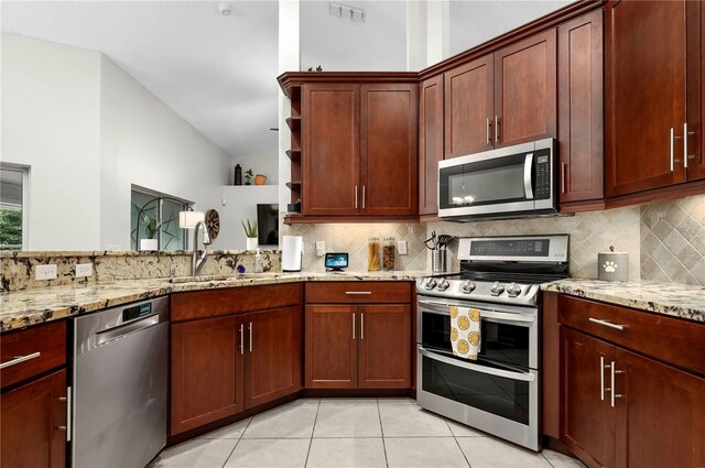 kitchen featuring stainless steel appliances, sink, lofted ceiling, light tile patterned flooring, and decorative backsplash