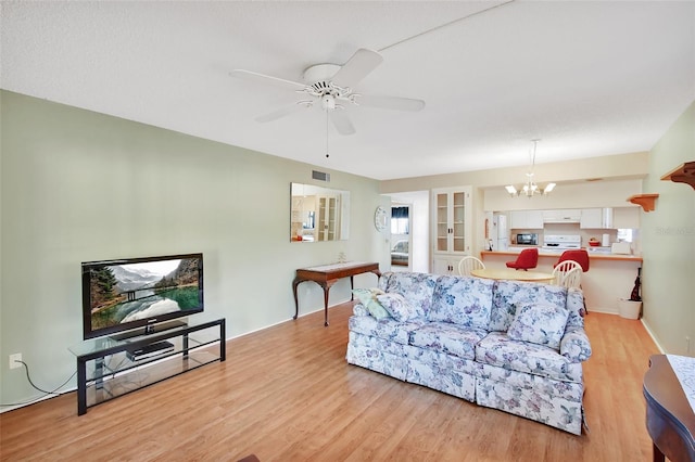 living room featuring light wood-style floors, visible vents, and ceiling fan with notable chandelier