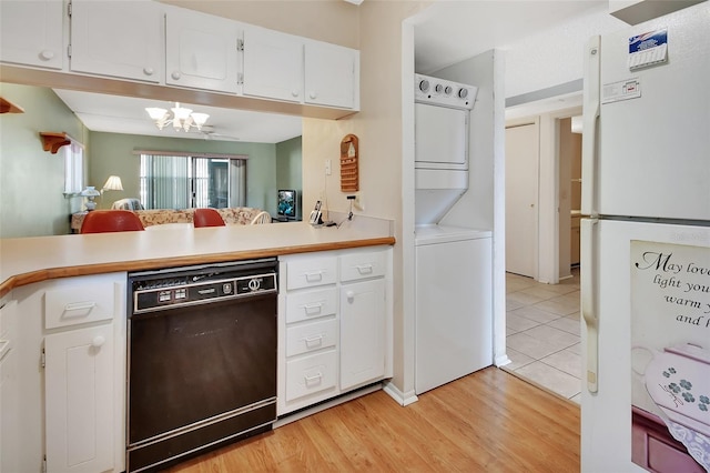 kitchen with white cabinets, white refrigerator, light hardwood / wood-style flooring, stacked washing maching and dryer, and black dishwasher