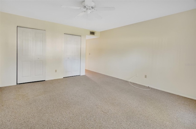 unfurnished bedroom with carpet flooring, ceiling fan, and two closets