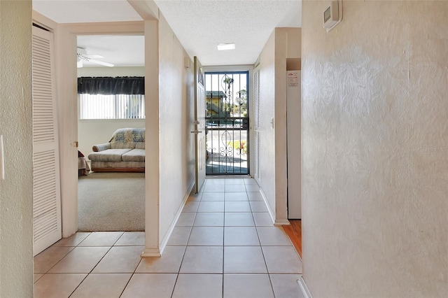 corridor featuring light tile patterned flooring and a textured ceiling