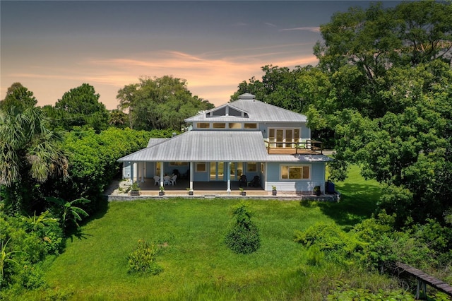 back house at dusk with a lawn