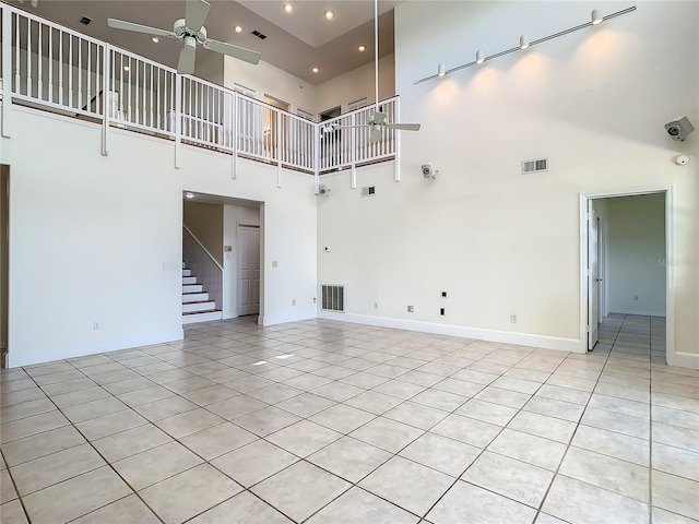 unfurnished living room with ceiling fan, a towering ceiling, and light tile patterned flooring