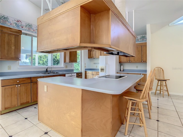 kitchen featuring white appliances, sink, a kitchen breakfast bar, light tile patterned floors, and a center island with sink