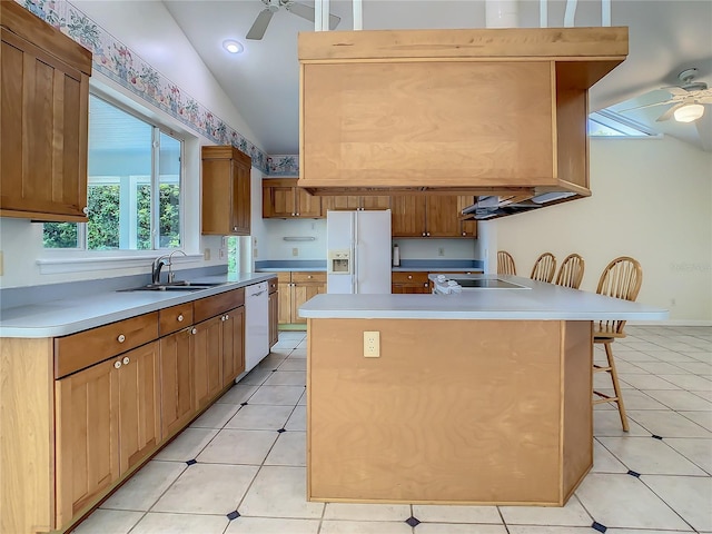 kitchen featuring lofted ceiling, a center island, sink, white appliances, and a breakfast bar area