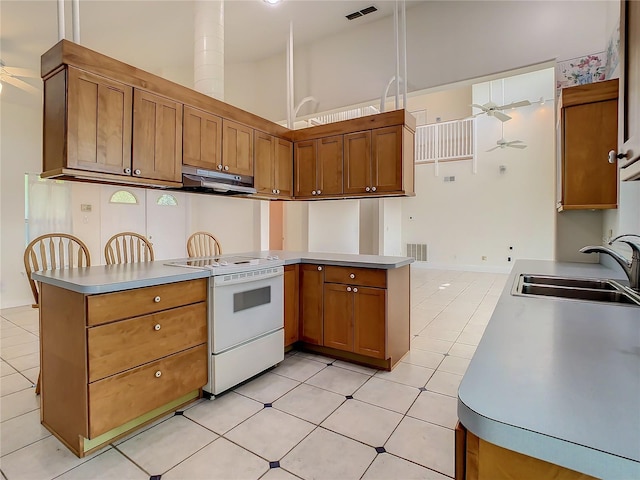 kitchen with ceiling fan, kitchen peninsula, a towering ceiling, sink, and white electric stove