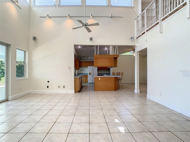 kitchen featuring ceiling fan, light tile patterned flooring, white fridge with ice dispenser, and a high ceiling