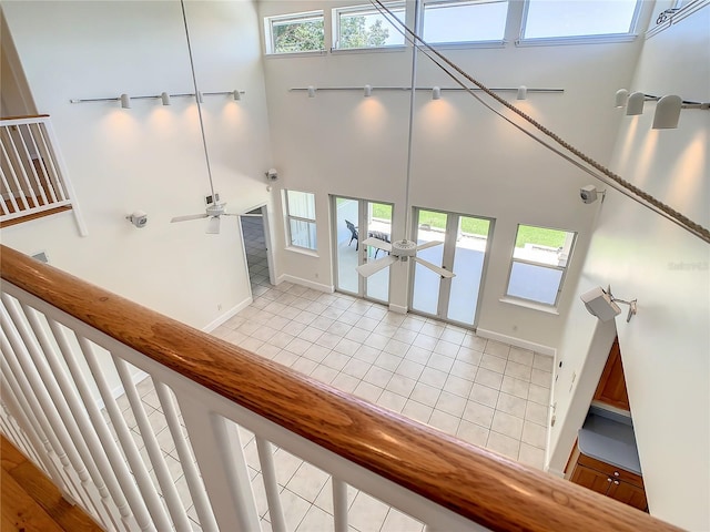 staircase with ceiling fan, tile patterned floors, and a towering ceiling