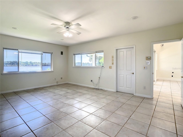 unfurnished room featuring ceiling fan, light tile patterned floors, and a water view