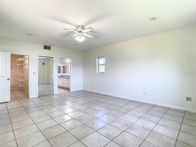 unfurnished bedroom featuring a spacious closet, a closet, light tile patterned flooring, ceiling fan, and ensuite bathroom