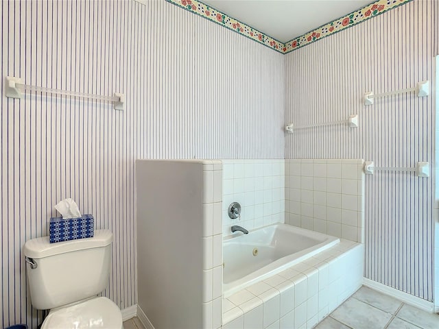 bathroom featuring toilet, tile patterned floors, and tiled tub