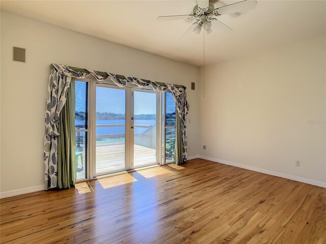 spare room with ceiling fan, light hardwood / wood-style flooring, and a water view