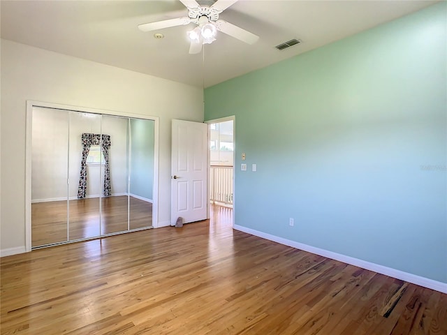 unfurnished bedroom with ceiling fan, a closet, and hardwood / wood-style floors