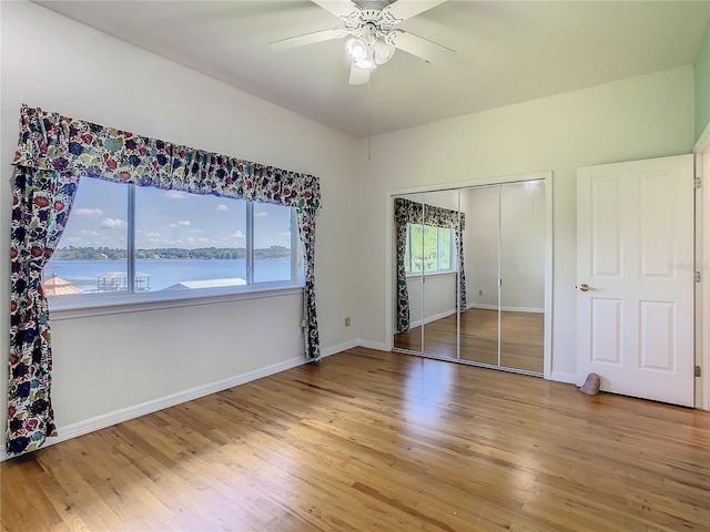 unfurnished bedroom featuring ceiling fan, multiple windows, a closet, and a water view