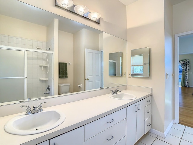 bathroom with toilet, vanity, tile patterned floors, and walk in shower