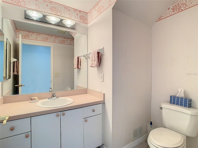 bathroom with toilet, vanity, and lofted ceiling