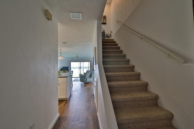 stairway featuring hardwood / wood-style flooring, a textured ceiling, and ceiling fan