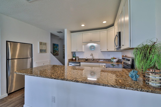 kitchen with dark stone counters, dark wood-type flooring, white cabinetry, sink, and stainless steel appliances