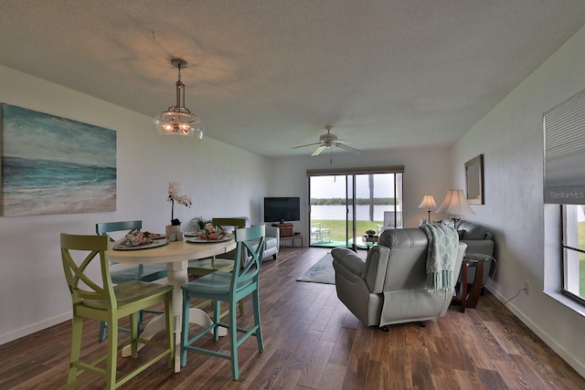 dining area with ceiling fan with notable chandelier, a textured ceiling, and dark hardwood / wood-style flooring