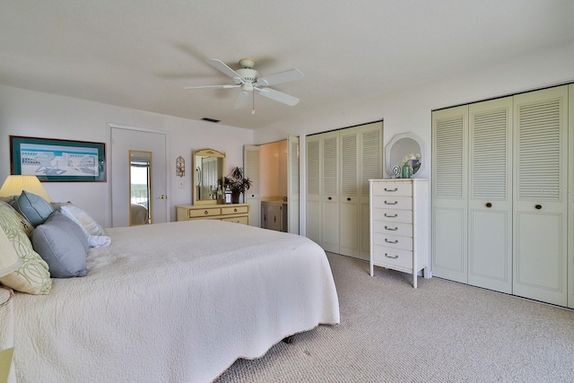 bedroom with ceiling fan, two closets, and light colored carpet