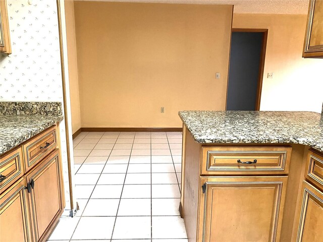 kitchen with stone countertops, light tile patterned floors, and a textured ceiling