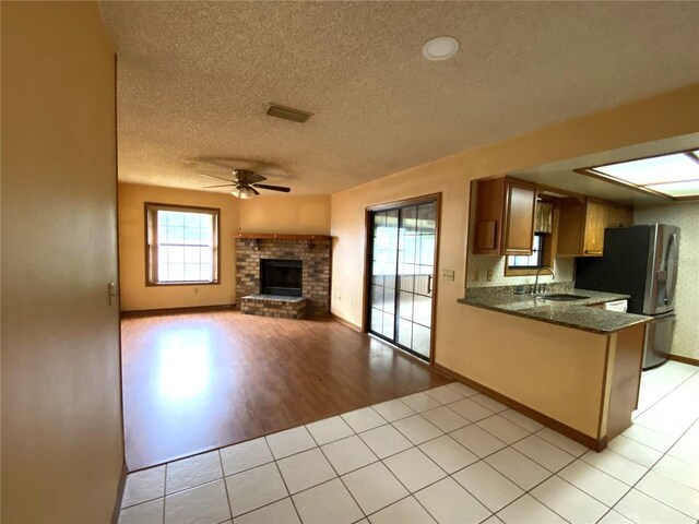 kitchen with stainless steel refrigerator with ice dispenser, sink, kitchen peninsula, ceiling fan, and light tile patterned floors