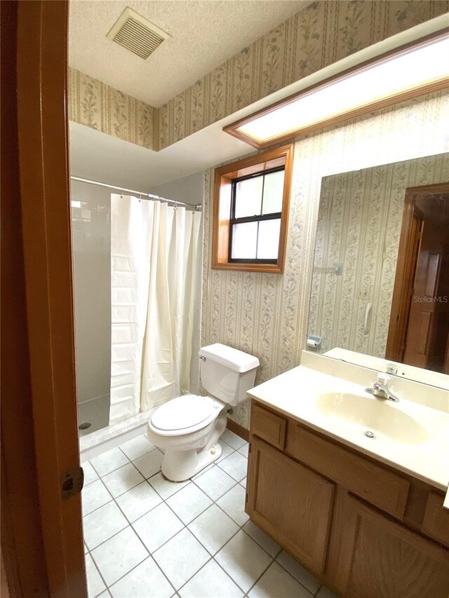 bathroom with vanity, toilet, walk in shower, and tile patterned flooring