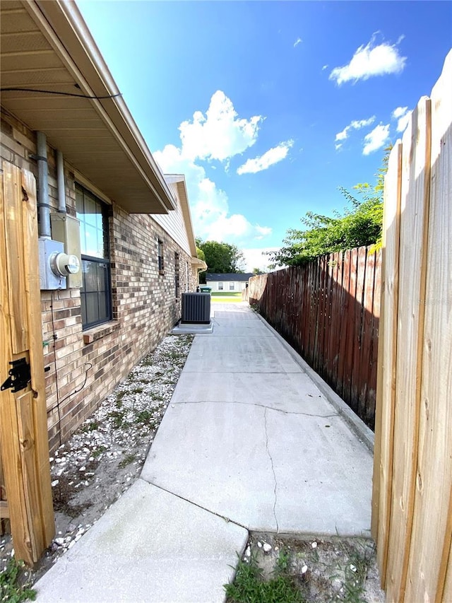 view of home's exterior featuring a patio, fence, central AC, and brick siding