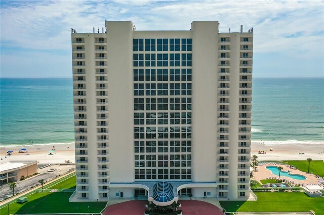 view of building exterior with a water view and a beach view