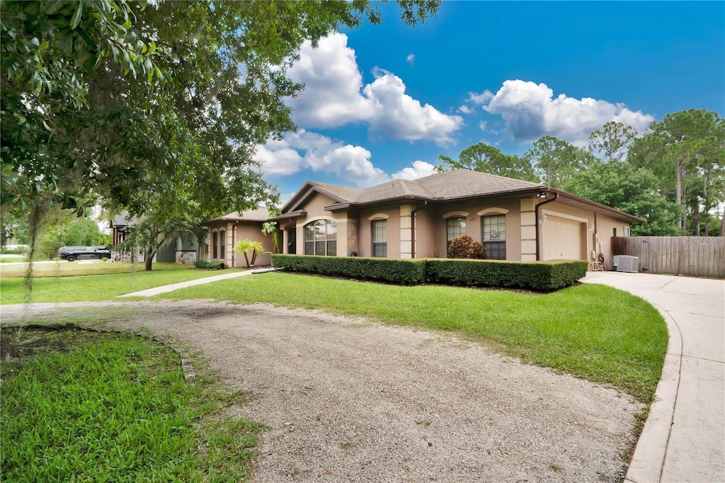 view of front of house with central AC, a garage, and a front lawn