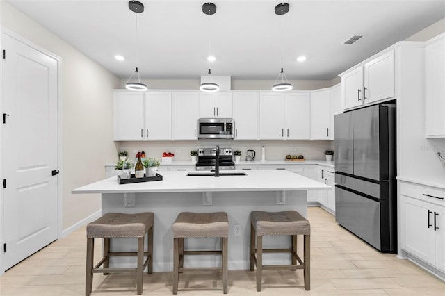 kitchen with appliances with stainless steel finishes, pendant lighting, and a center island with sink