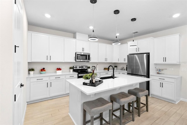 kitchen with hanging light fixtures, stainless steel appliances, and white cabinets